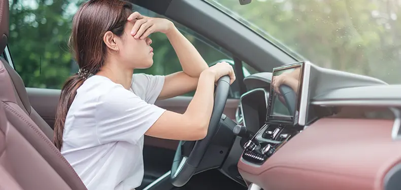 A photo of a woman driver holding her head in her hand.